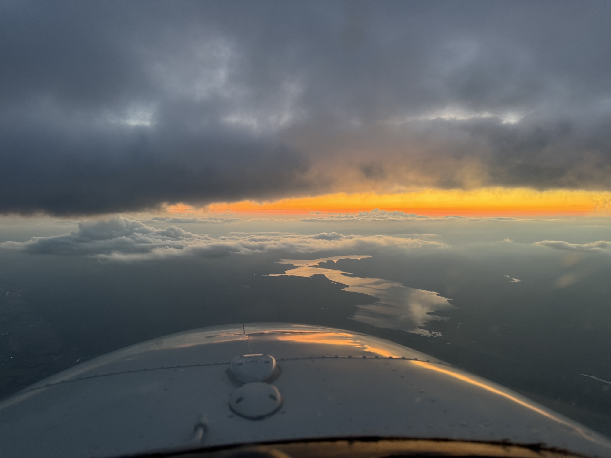 Cockpit view over water at sunset from a Baron 58